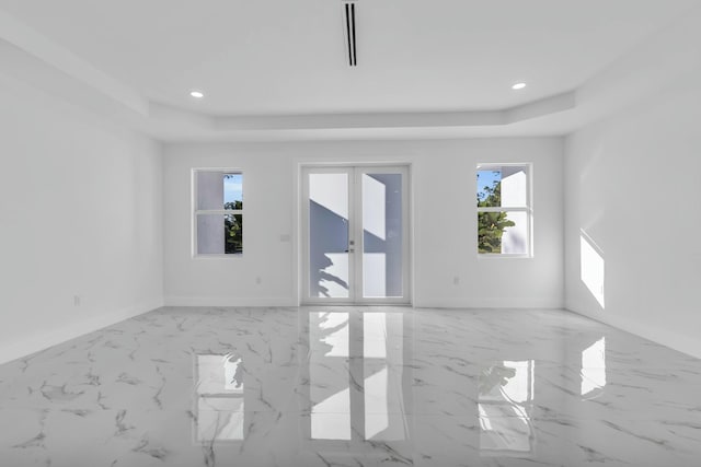 empty room with french doors and a raised ceiling