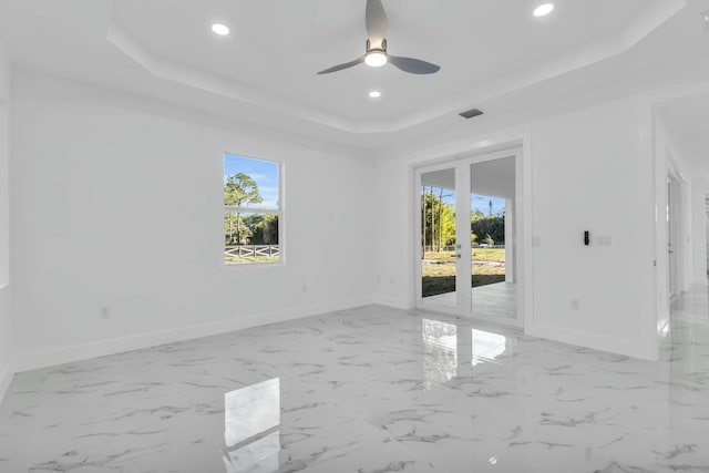 spare room with french doors, a healthy amount of sunlight, ceiling fan, and a tray ceiling