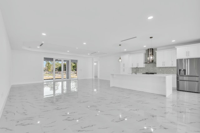 kitchen with wall chimney exhaust hood, tasteful backsplash, stainless steel fridge, pendant lighting, and white cabinets