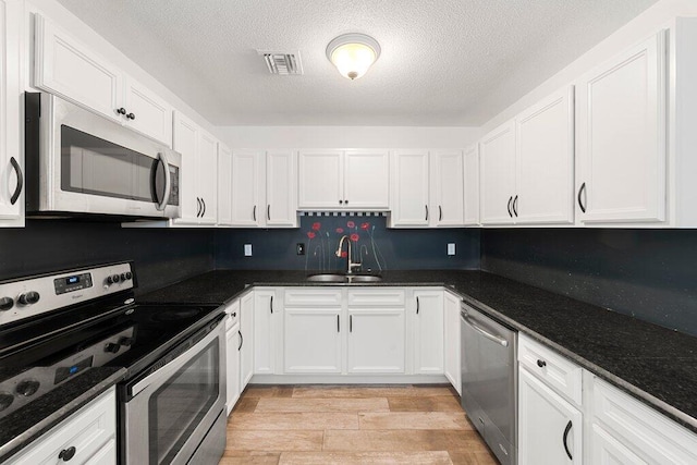 kitchen featuring white cabinetry, appliances with stainless steel finishes, sink, and light wood-type flooring