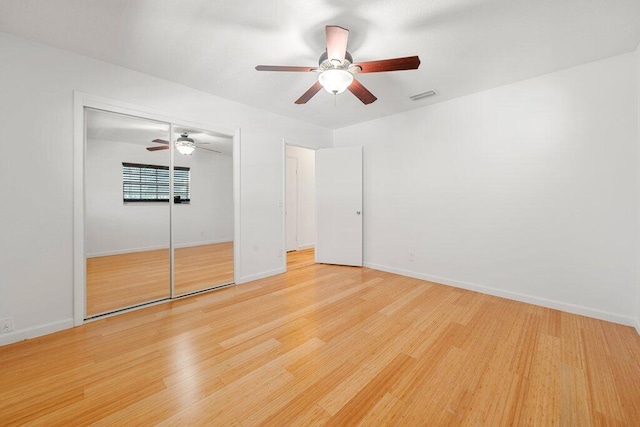 unfurnished bedroom featuring hardwood / wood-style flooring, ceiling fan, and a closet