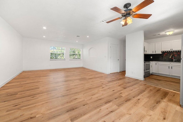 unfurnished living room with sink, light hardwood / wood-style flooring, and ceiling fan