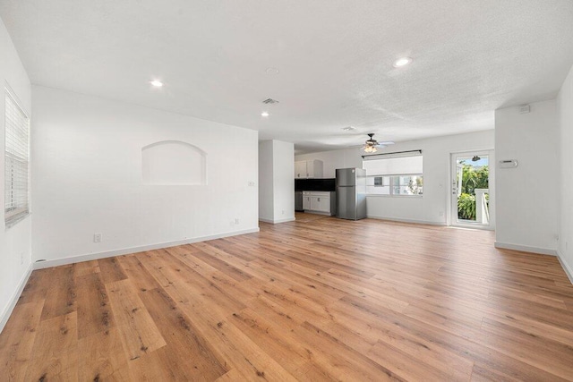 unfurnished living room with a textured ceiling, light hardwood / wood-style floors, and ceiling fan