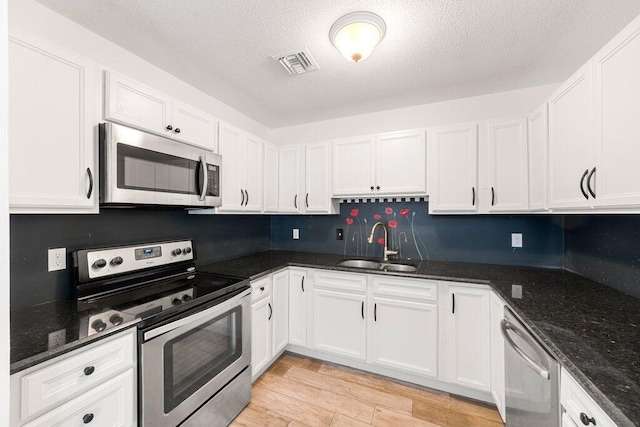 kitchen with dark stone countertops, sink, white cabinets, and appliances with stainless steel finishes