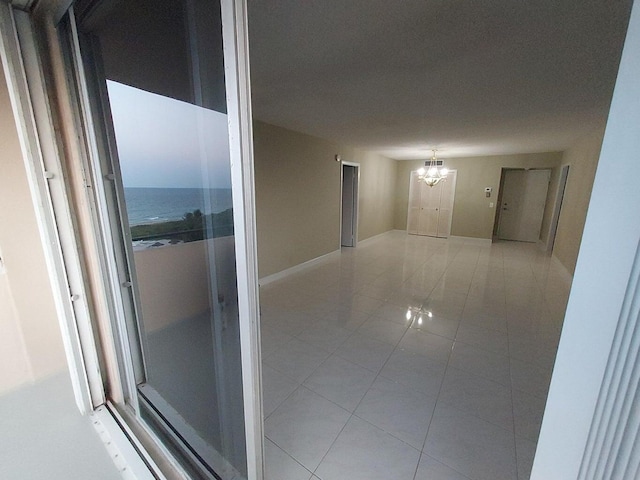 corridor with tile patterned flooring, a water view, and an inviting chandelier