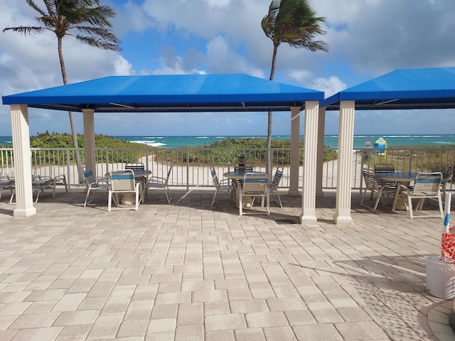 view of patio with a gazebo, a water view, and a view of the beach