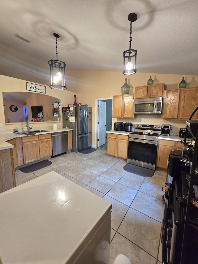 kitchen featuring decorative light fixtures, lofted ceiling, sink, light tile patterned floors, and stainless steel appliances