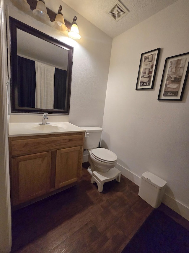 bathroom with hardwood / wood-style flooring, vanity, a textured ceiling, and toilet