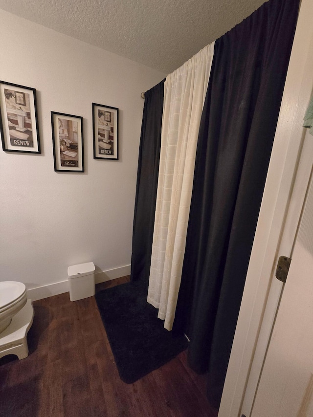 bathroom featuring hardwood / wood-style flooring, toilet, and a textured ceiling