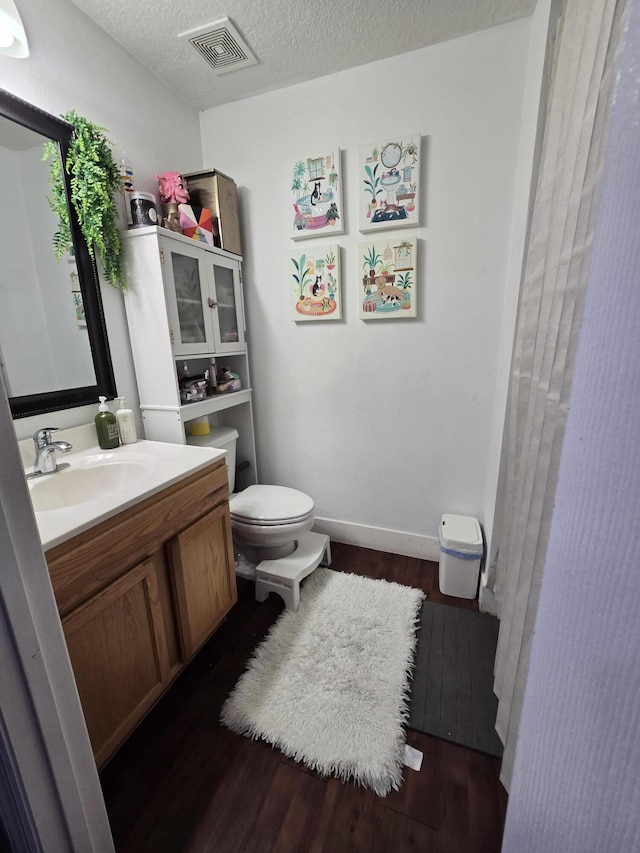 bathroom featuring vanity, hardwood / wood-style flooring, toilet, and a textured ceiling