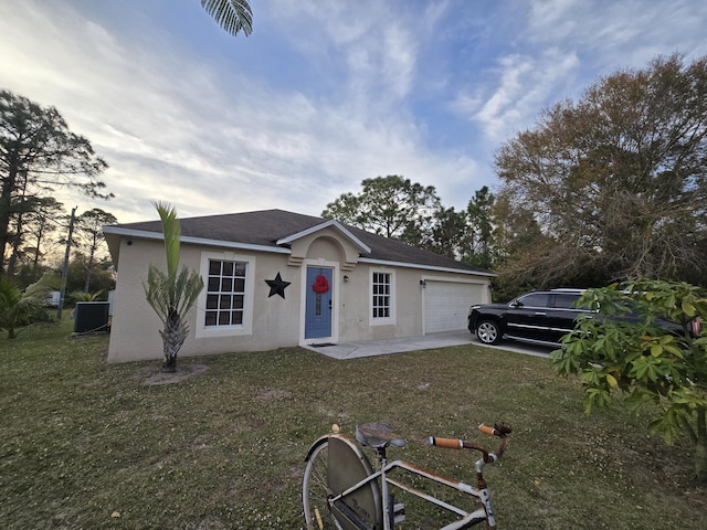 ranch-style house with a yard, a garage, and central air condition unit