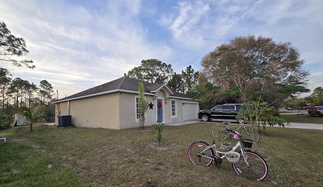 view of front of house featuring a garage, central AC unit, and a front yard