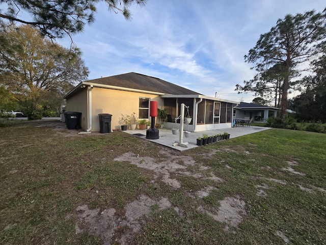 rear view of property featuring a patio area, a sunroom, and a lawn