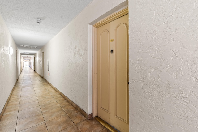 hall with light tile patterned flooring and a textured ceiling