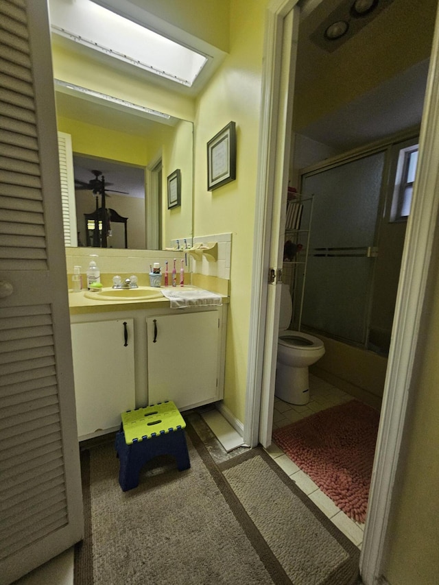 full bathroom featuring tile patterned flooring, vanity, combined bath / shower with glass door, and toilet