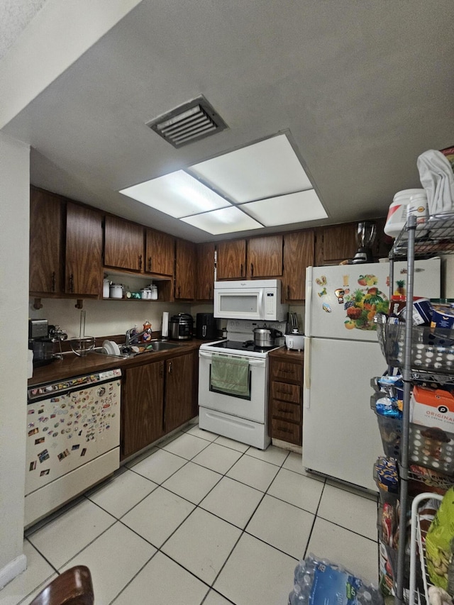 kitchen featuring light tile patterned flooring, white appliances, sink, and dark brown cabinets