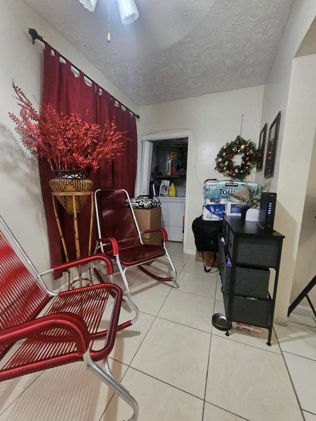 living area featuring light tile patterned floors, washer / clothes dryer, and a textured ceiling