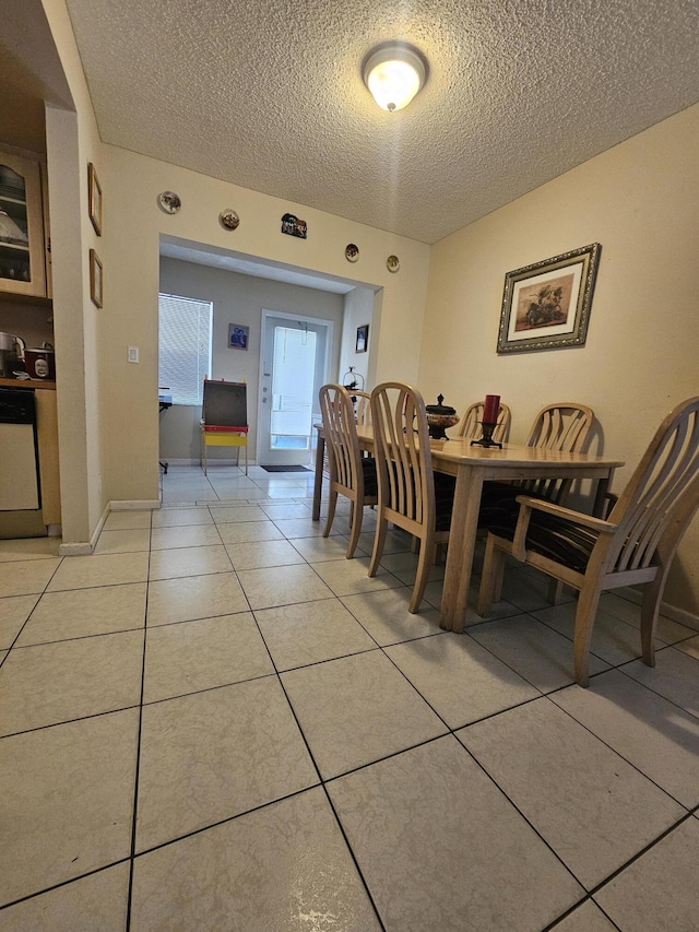 dining space featuring a textured ceiling and light tile patterned floors