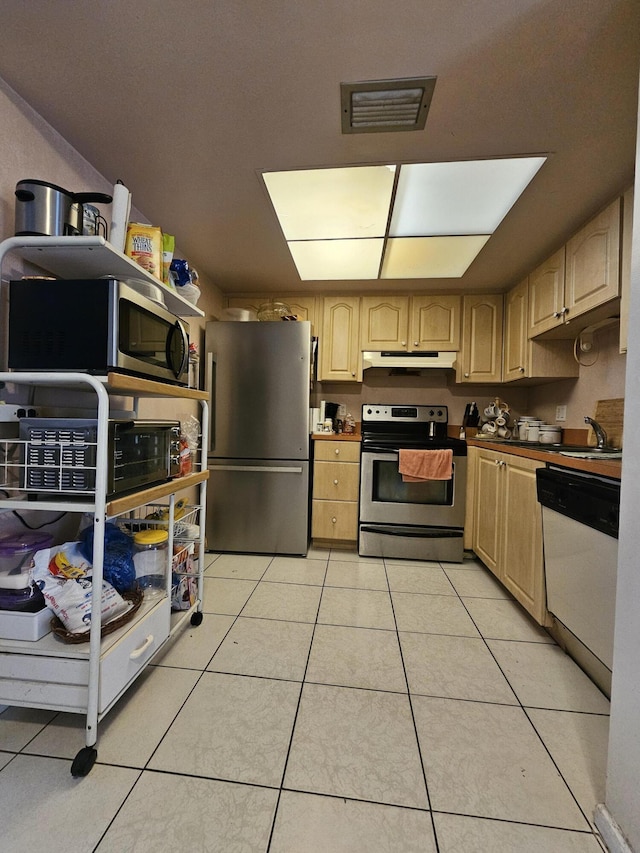 kitchen with light tile patterned flooring, appliances with stainless steel finishes, sink, and light brown cabinets