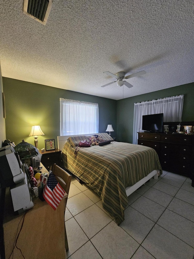 tiled bedroom featuring ceiling fan and a textured ceiling