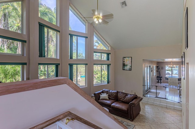 tiled living room with ceiling fan with notable chandelier, plenty of natural light, and high vaulted ceiling