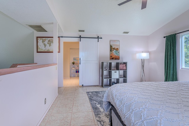 tiled bedroom with ceiling fan and a barn door