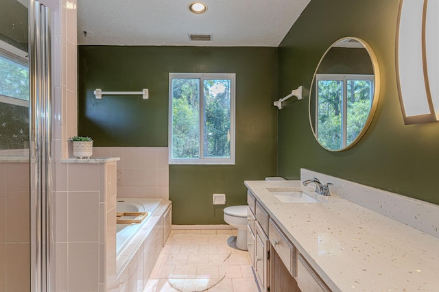 bathroom featuring tiled tub, tile patterned flooring, vanity, a textured ceiling, and toilet