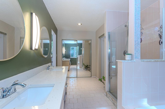 bathroom featuring vanity, a shower with door, tile patterned floors, and a textured ceiling