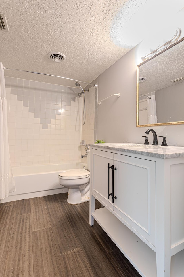 full bathroom with hardwood / wood-style flooring, shower / bath combo, vanity, a textured ceiling, and toilet