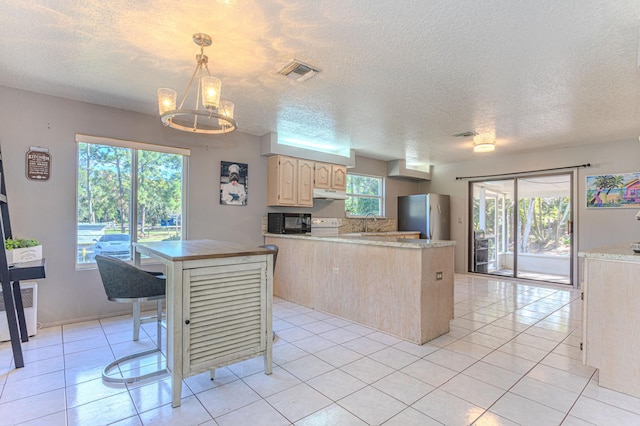 kitchen featuring decorative light fixtures, stainless steel fridge, a chandelier, a center island, and a healthy amount of sunlight