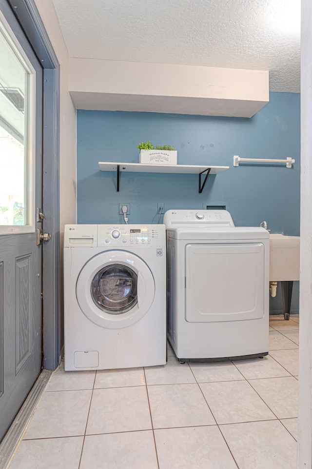 laundry room with washer and dryer, a textured ceiling, and light tile patterned flooring