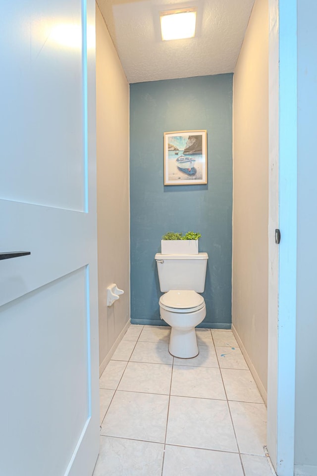 bathroom featuring a textured ceiling, tile patterned floors, and toilet