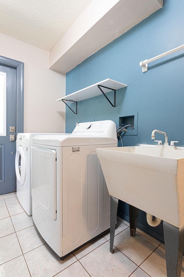 washroom with washing machine and dryer, a textured ceiling, and light tile patterned floors