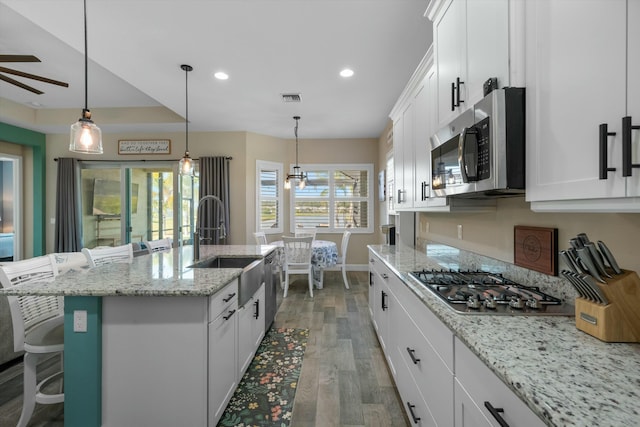 kitchen featuring sink, a breakfast bar area, a center island with sink, stainless steel appliances, and white cabinets