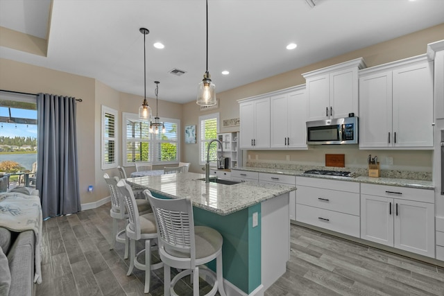 kitchen featuring an island with sink, appliances with stainless steel finishes, sink, and white cabinets