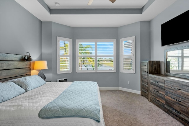 carpeted bedroom with ceiling fan and a raised ceiling