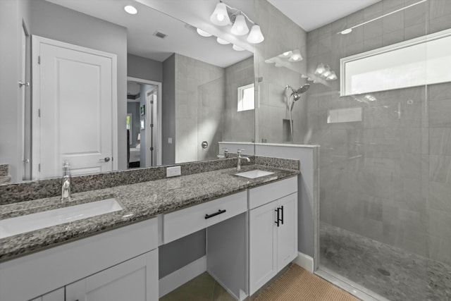 bathroom with tiled shower, vanity, and tile patterned floors