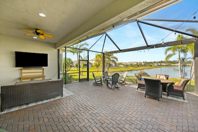 view of patio / terrace with an outdoor living space, a water view, ceiling fan, and a lanai