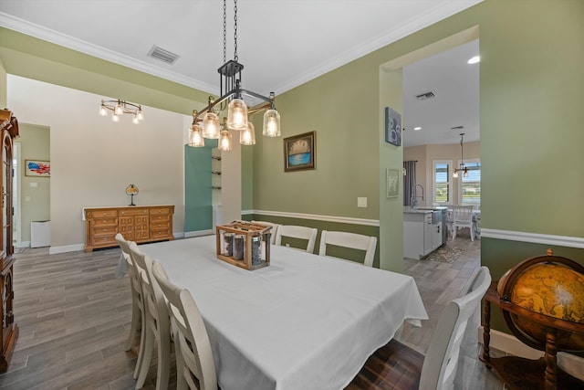 dining area featuring hardwood / wood-style flooring, crown molding, and sink