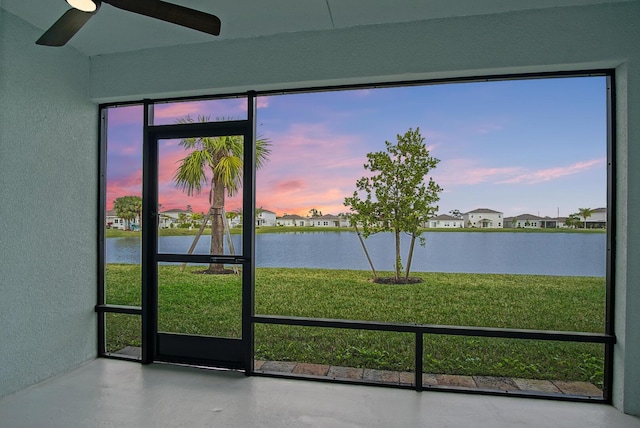 unfurnished sunroom featuring a wealth of natural light, a water view, and ceiling fan