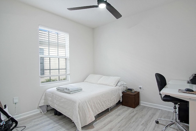 bedroom featuring ceiling fan, light hardwood / wood-style floors, and multiple windows