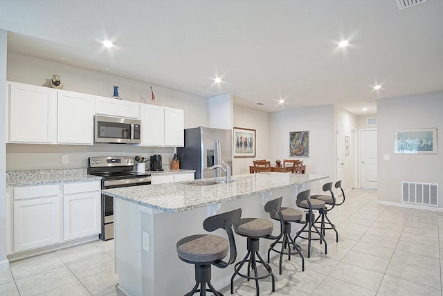 kitchen with appliances with stainless steel finishes, sink, a center island with sink, and white cabinets