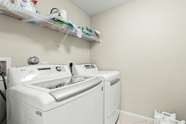 clothes washing area featuring washer and dryer and light tile patterned floors