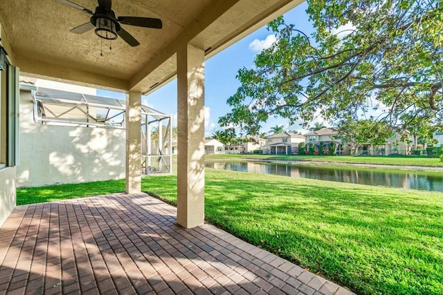 view of patio / terrace featuring ceiling fan, a water view, and glass enclosure