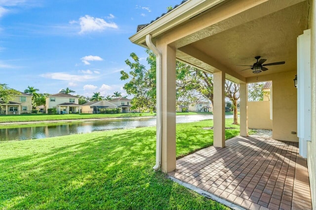 view of yard with a water view, ceiling fan, and a patio area