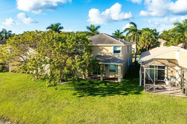 rear view of house with a yard, a patio, and glass enclosure