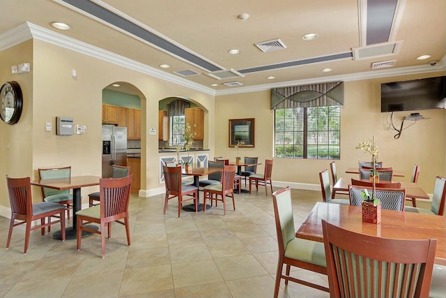 tiled dining space with ornamental molding and a raised ceiling