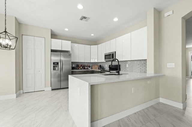 kitchen featuring pendant lighting, sink, stainless steel appliances, white cabinets, and kitchen peninsula