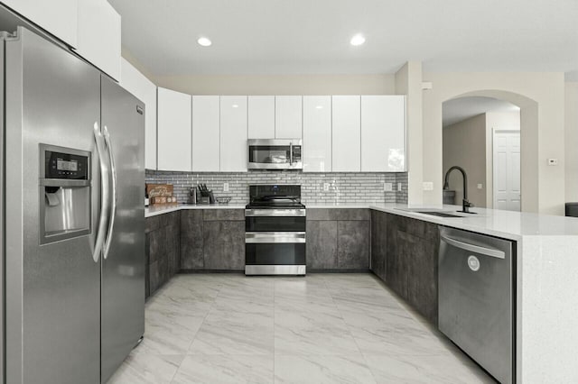 kitchen featuring stainless steel appliances, sink, white cabinets, and decorative backsplash