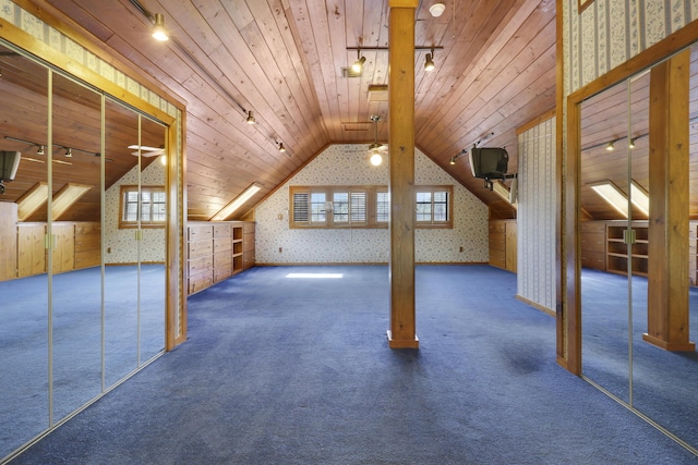 additional living space with dark colored carpet, lofted ceiling, a wealth of natural light, and wood ceiling